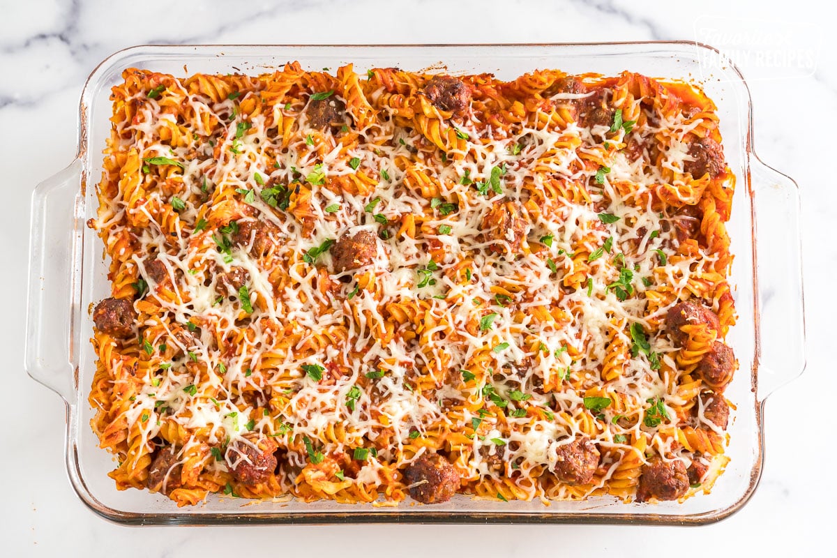 Baked Rotini in a baking dish garnished with cheese and parsley