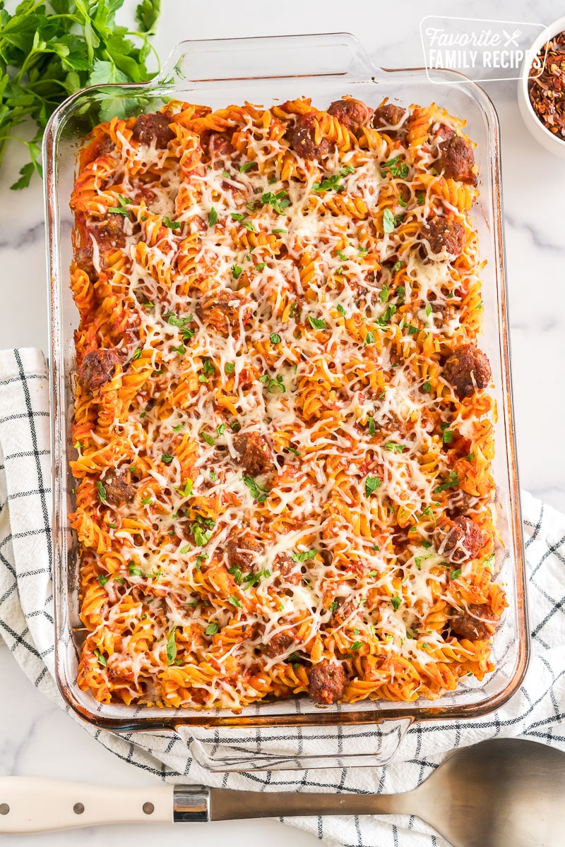 Baked Rotini in a baking dish garnished with cheese and parsley