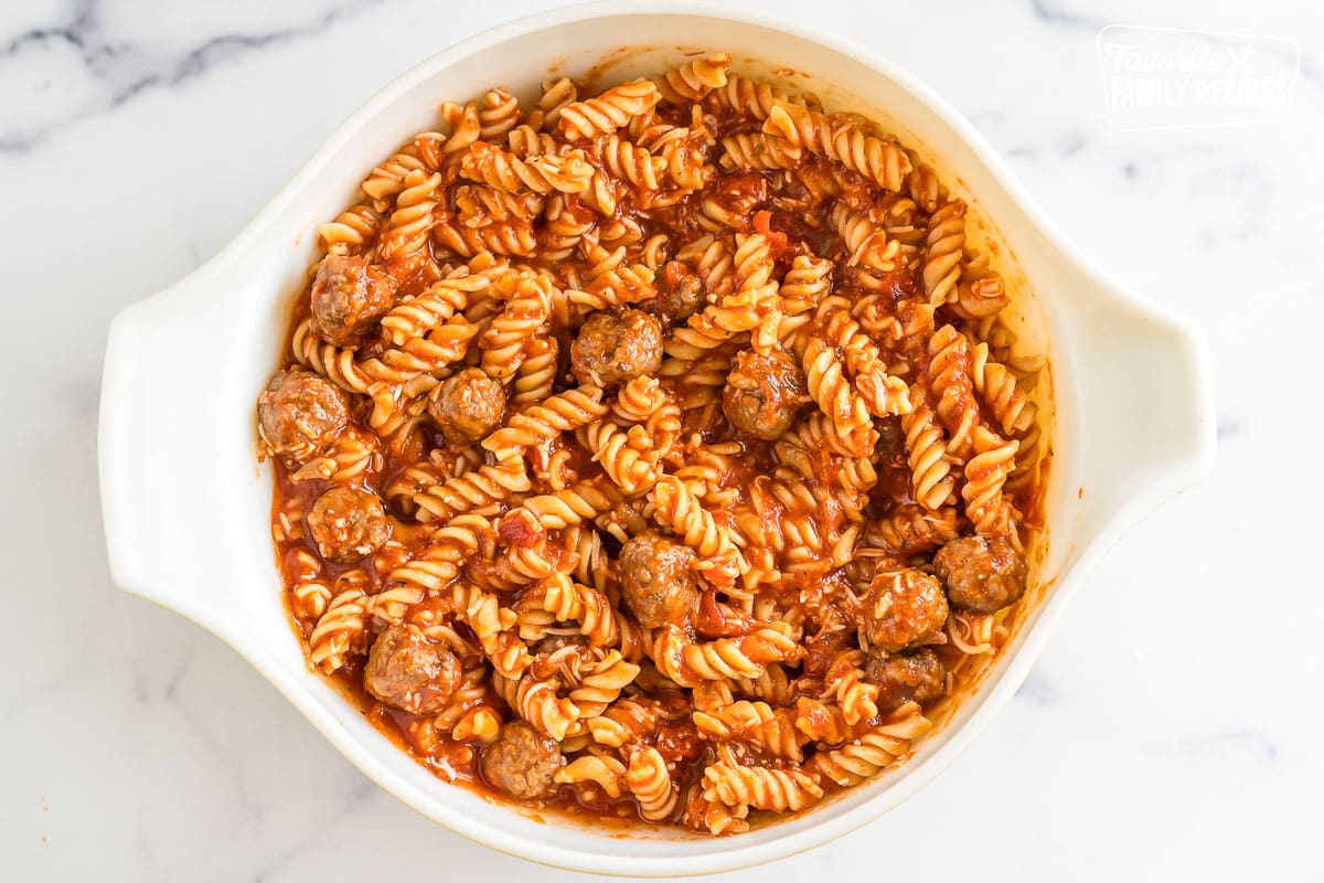 A bowl of pasta mixed with red sauce and meatballs