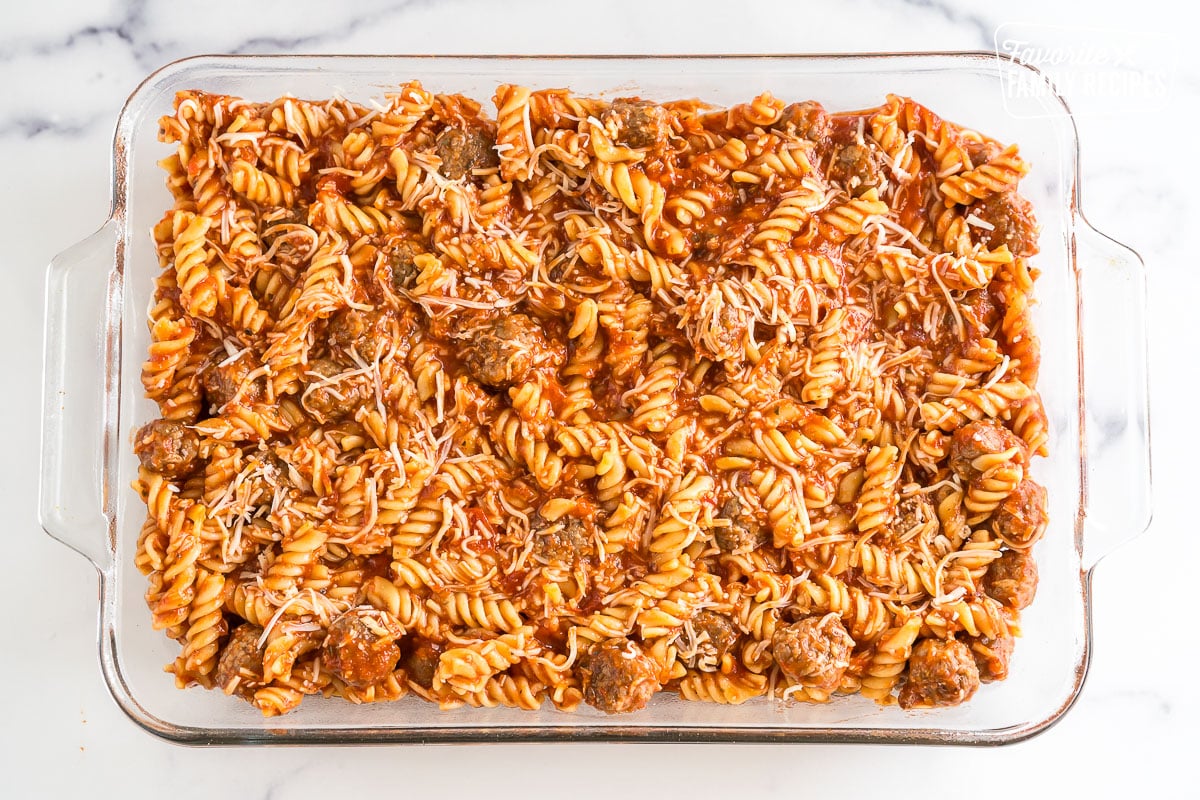 a baking dish filled with a mixture of pasta, red sauce, meatballs, and cheese