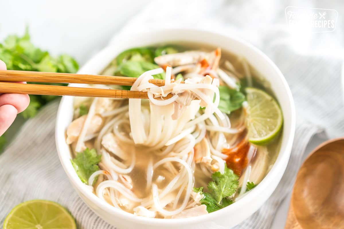 Chopsticks lifting noodles and meat out of a bowl.