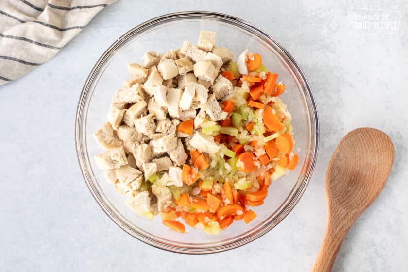 Mixing bowl with vegetables and cut pieces of chicken.