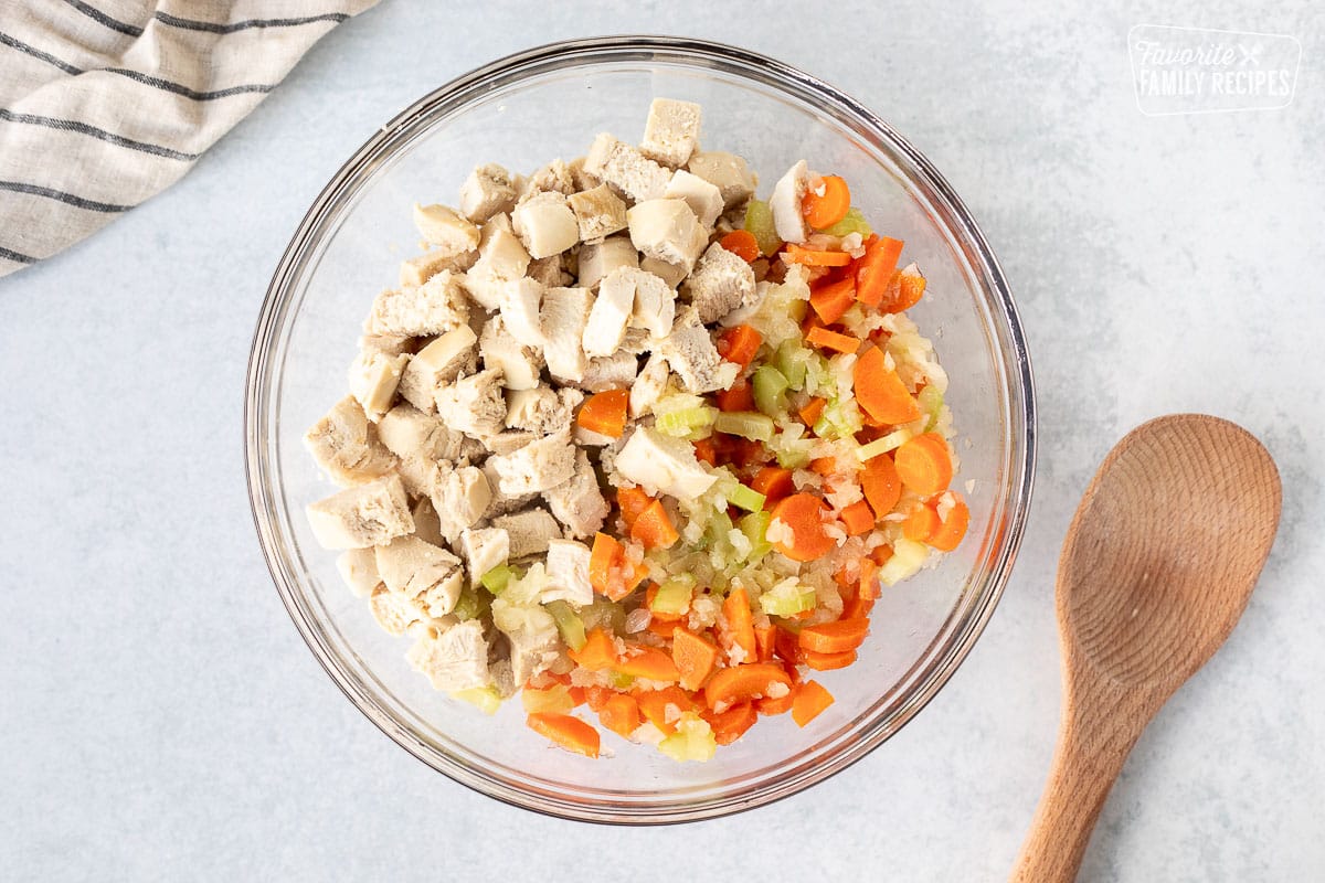 Mixing bowl with vegetables and cut pieces of chicken.