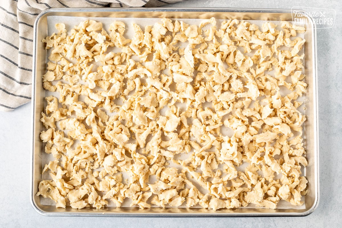 Cookie sheet lined with parchment paper and unbaked crumble topping.