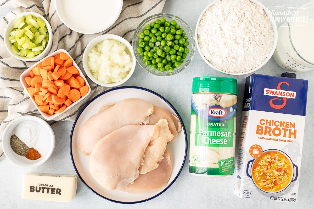 Ingredients to make Chicken Pot Pie Casserole including chicken, parmesan cheese, chicken broth, flour, milk, heavy cream, peans, onions, carrots, celery, butter and spices.