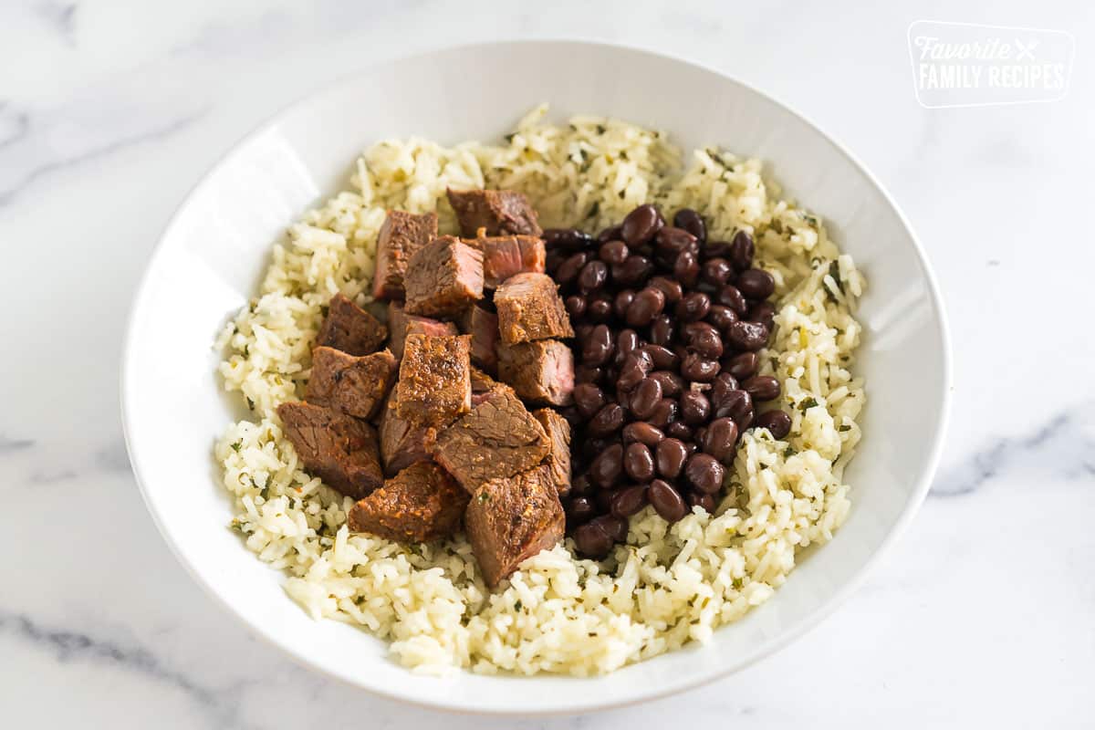 A bowl with rice, chipotle steak, and black beans