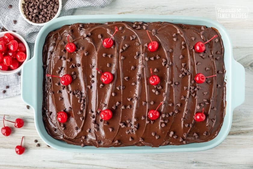 Chocolate chips and maraschino cherries on top of Chocolate Cherry Cake in a baking dish.