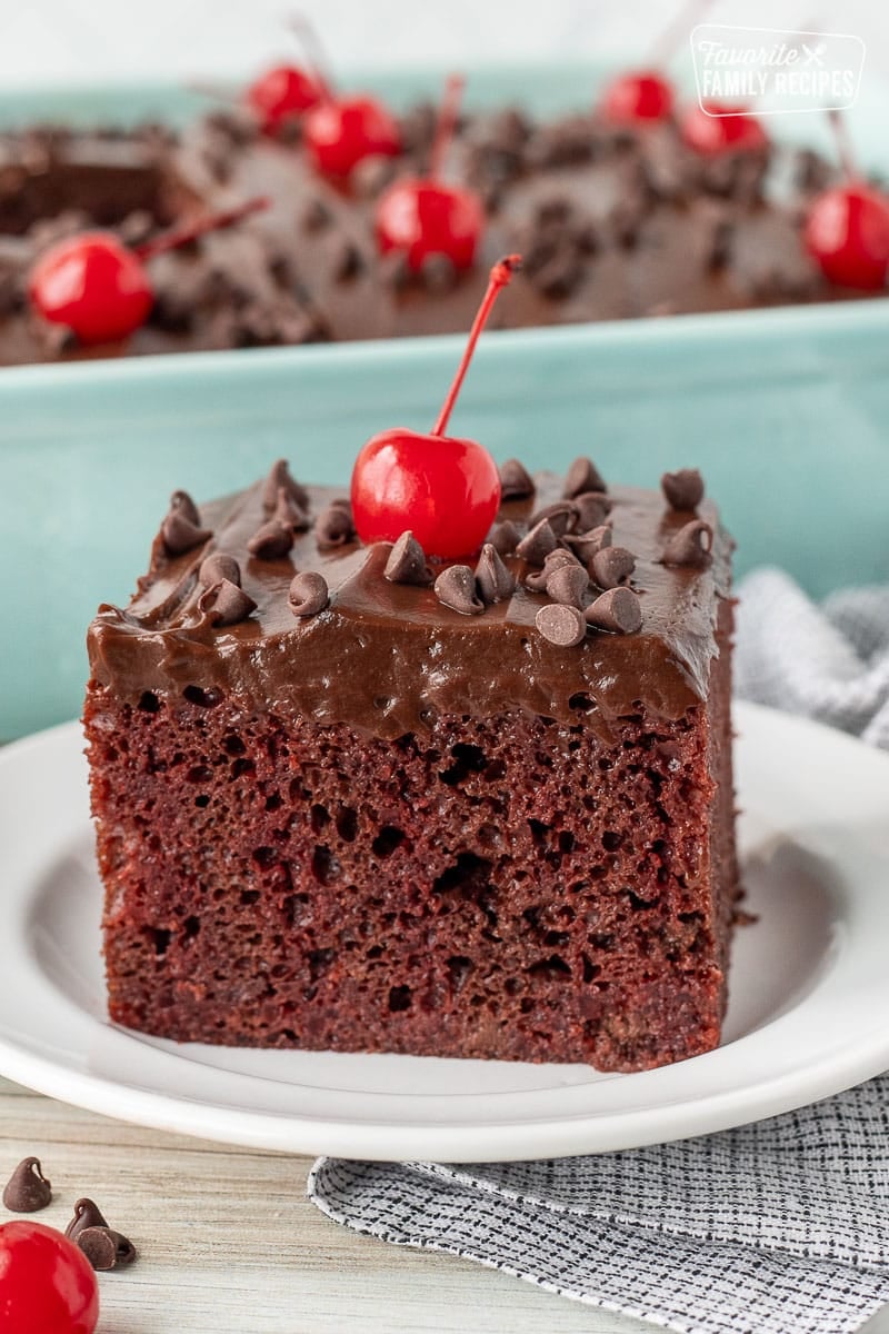 Slice of Chocolate Cherry Cake with chocolate chips and a maraschino cherry.