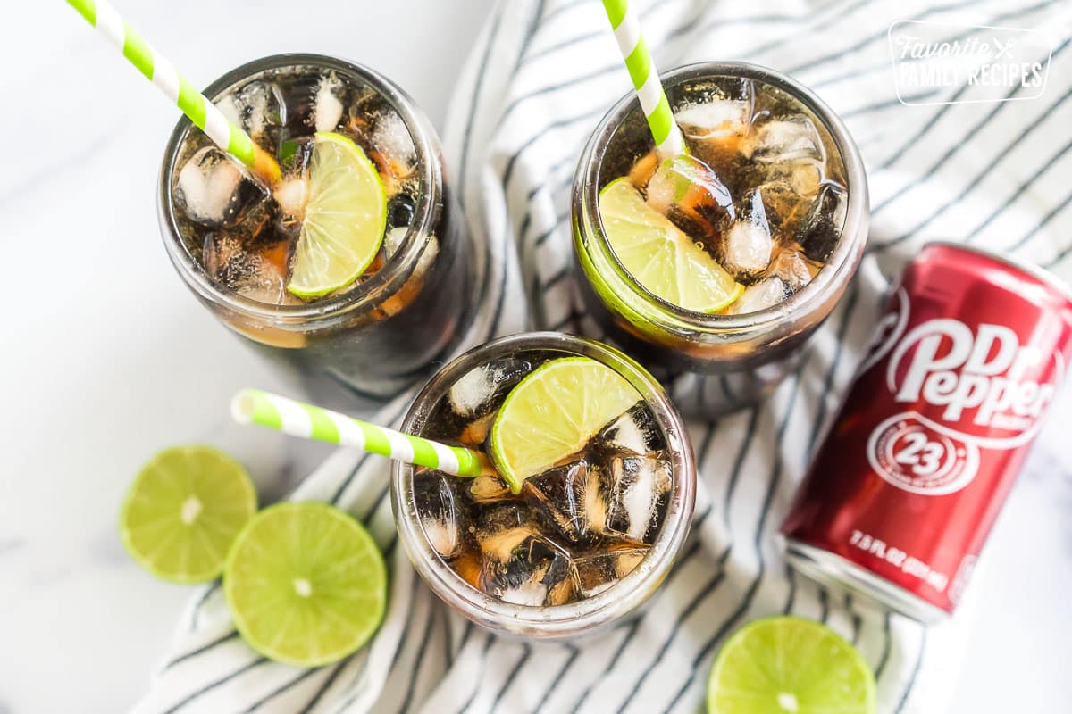 Three cups with soda, limes, ice, and flavoring