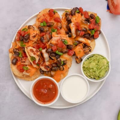 Overhead shot of Oven Nachos on a plate with guacamole, sour cream, and salsa