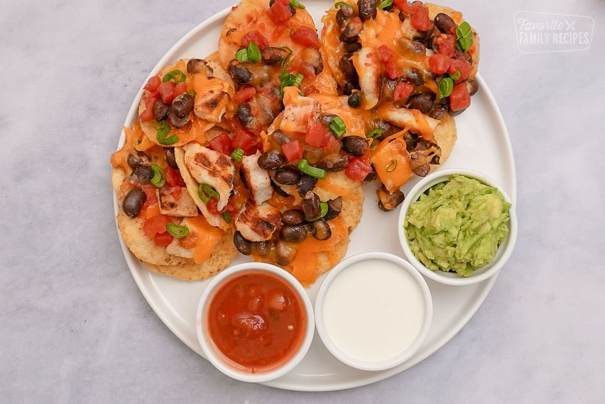 Close up Oven Nachos on a plate with guacamole, sour cream, and salsa from above