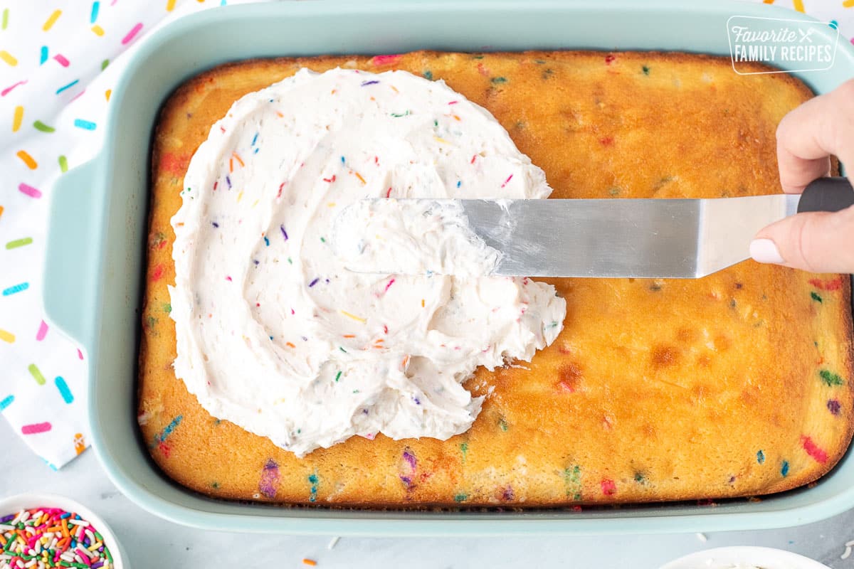 Spreading Funfetti Frosting on top of baked Funfetti Cake.
