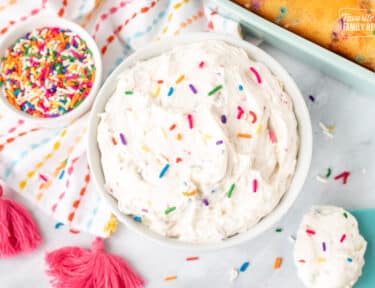 Bowl of white Funfetti frosting with colorful sprinkles.