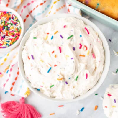 Bowl of white Funfetti frosting with colorful sprinkles.