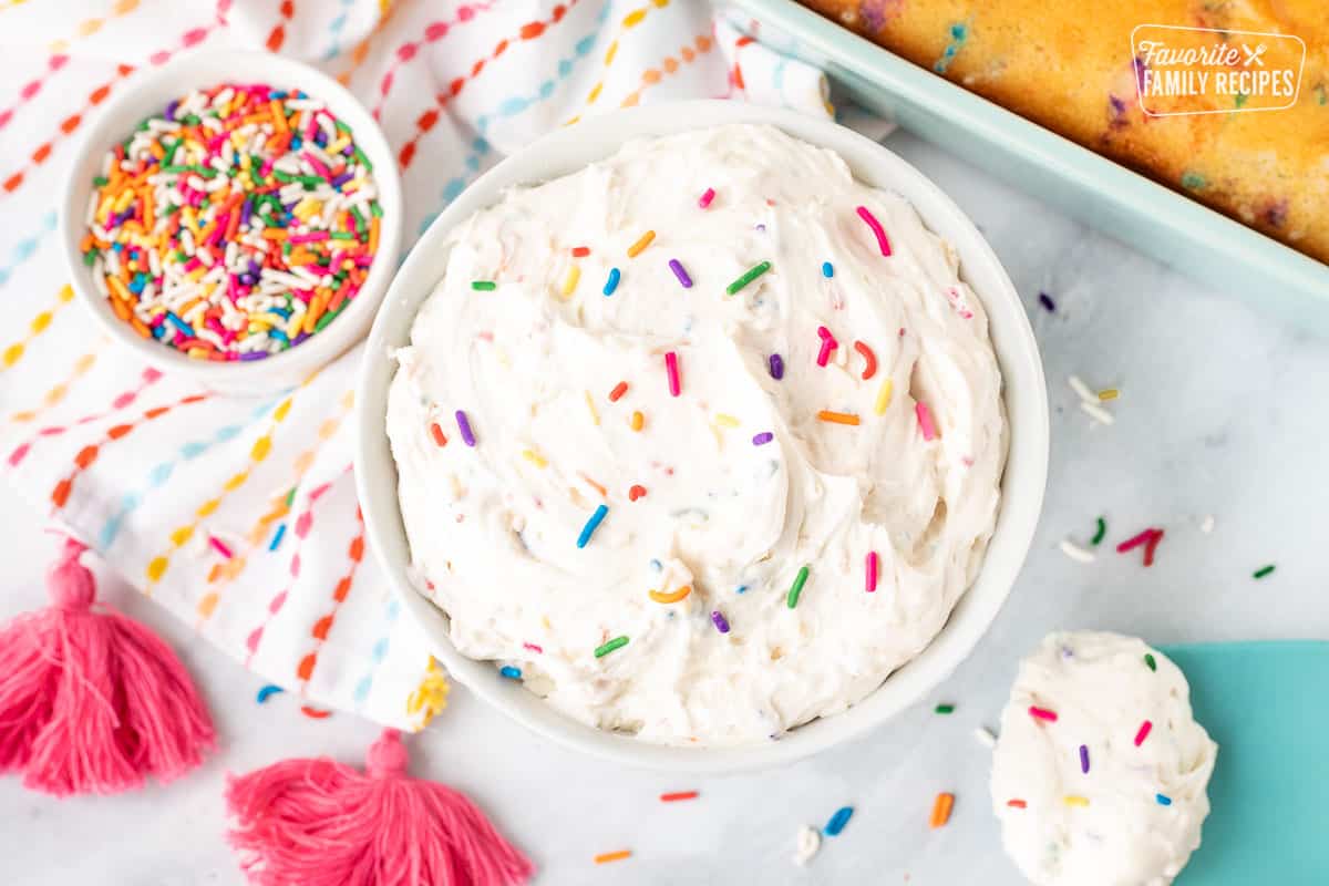 Bowl of white Funfetti frosting with colorful sprinkles.