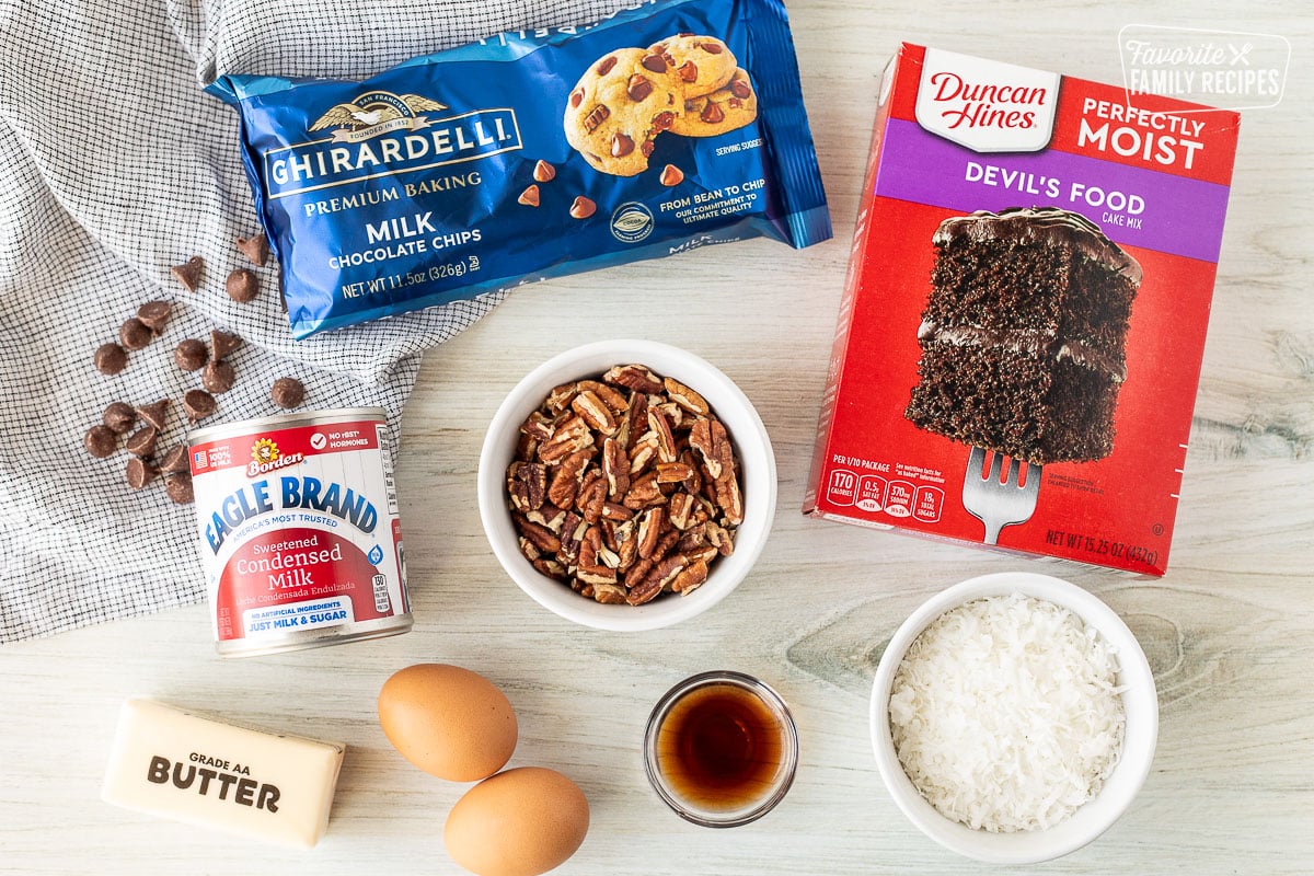 Ingredients to make German Chocolate Cookie Bars including devil's food cake mix, milk chocolate chips, vanilla, coconut, eggs, butter, sweetened condensed milk and pecans.