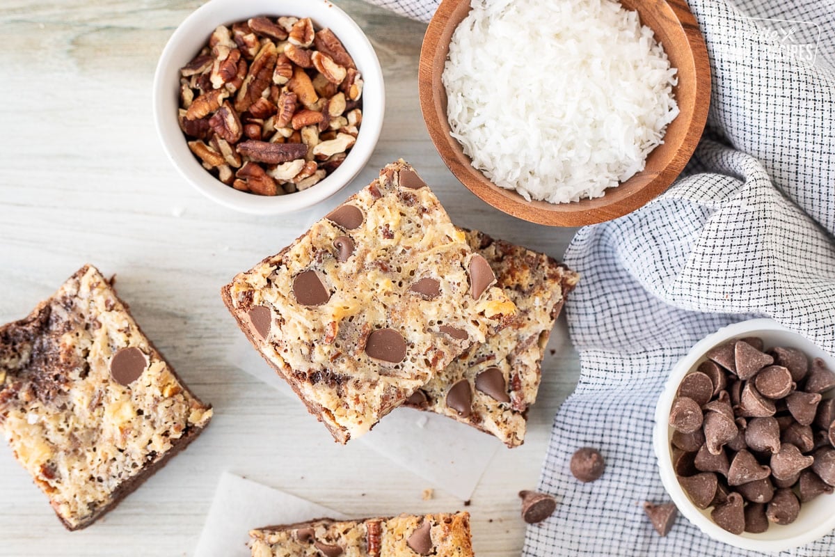 German Chocolate Cookie Bars cut in squares. Coconut, pecans and milk chocolate chips on the side.