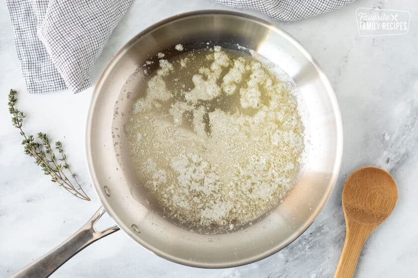 Sauce pan with melted butter and wooden spoon.