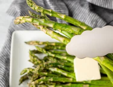 Tongs grabbing Sweet Sautéed Asparagus.