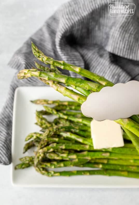 Tongs grabbing Sweet Sautéed Asparagus.