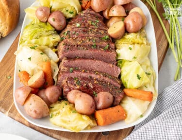 Instant Pot Corned Beef and Cabbage on a tray with carrots and red potatoes.