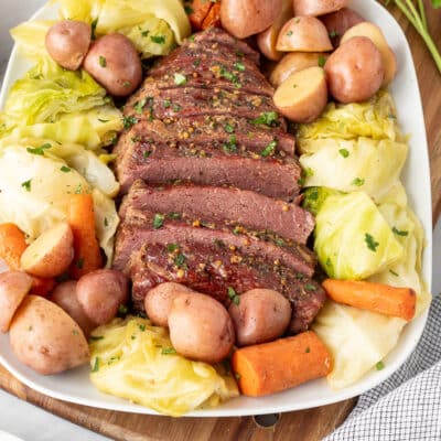 Instant Pot Corned Beef and Cabbage on a tray with carrots and red potatoes.
