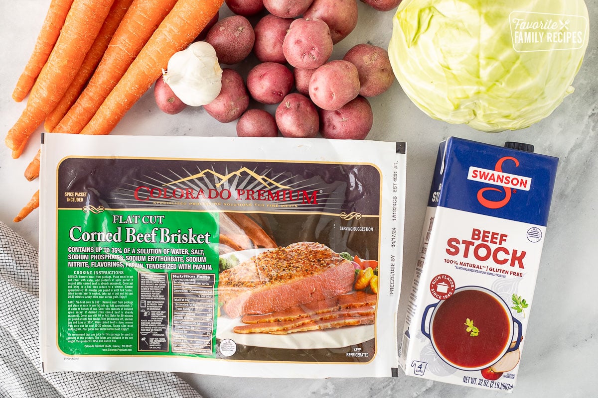 Ingredients to make Instant Pot Corned Beef and Cabbage including beef broth, red potatoes, green cabbage, corned beef brisket, garlic and carrots.
