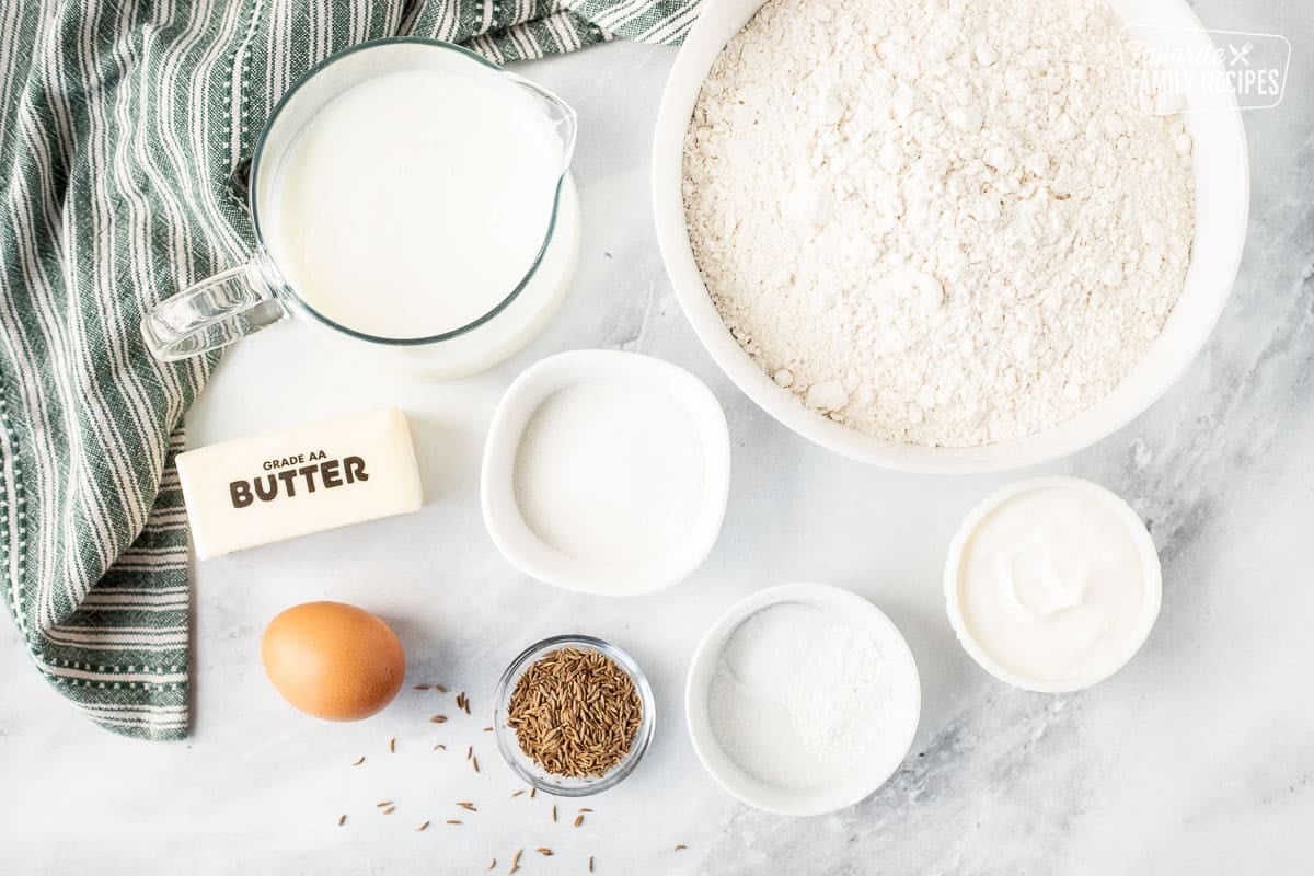 Ingredients to make Irish Soda Bread including flour, buttermilk, butter, egg, caraway seeds, baking soda, baking powder, salt, sour cream and sugar.