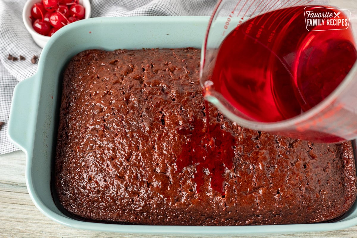 Pouring cherry jello on top of baked poked chocolate cake.