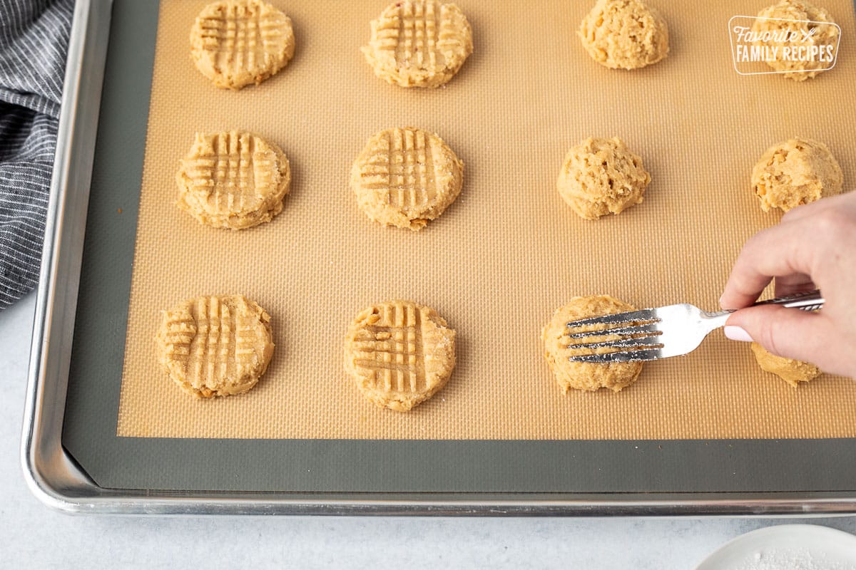 Pressing a peanut butter cookie dough ball with a fork.