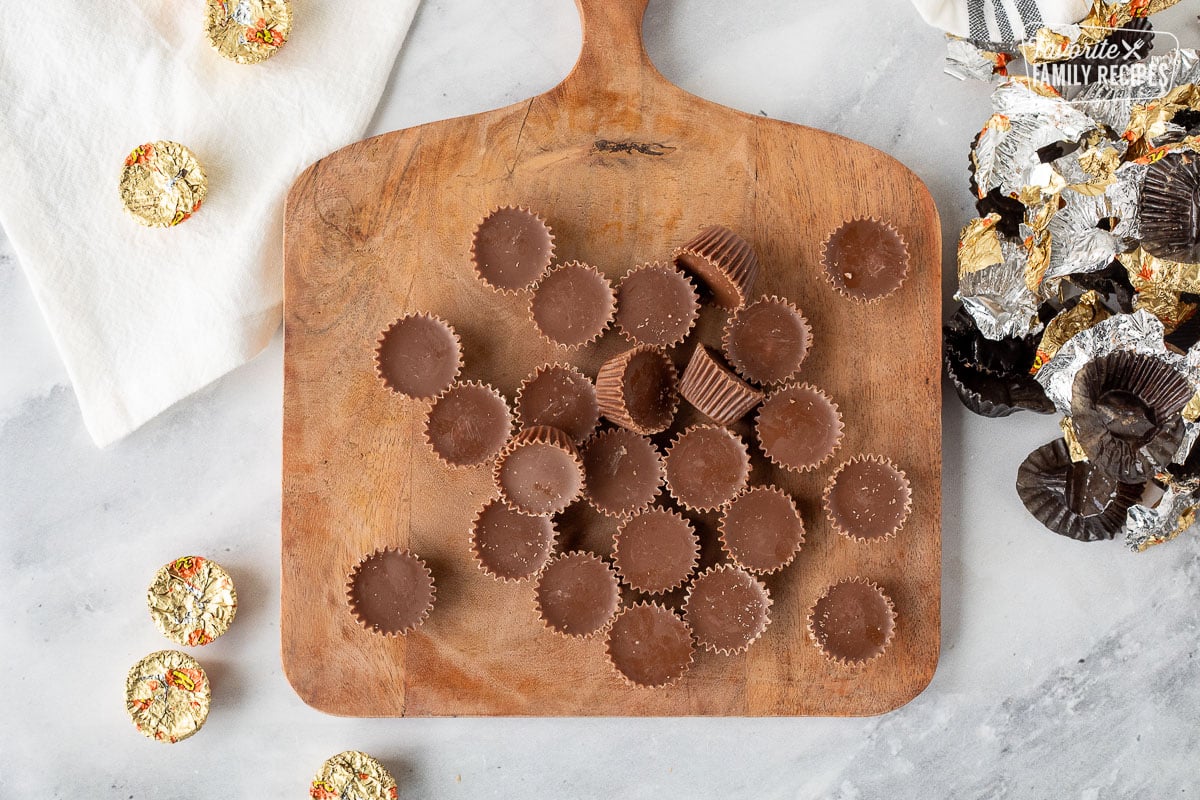 Cutting board with unwrapped Reese's Peanut Butter Cup chocolates.