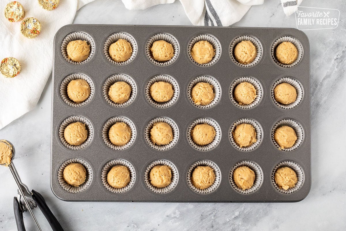 Balls of cookie dough in miniature muffin liners.