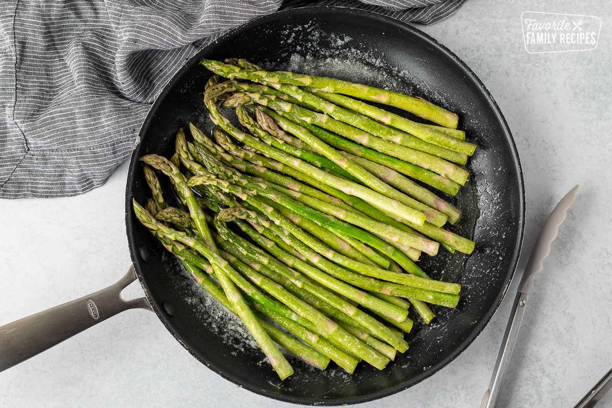 Skillet Sautéing Asparagus with tongs on the side.