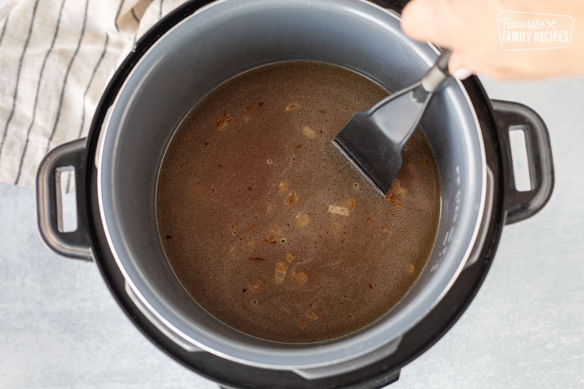 Scraping the bottom of Instant Pot with spatula.