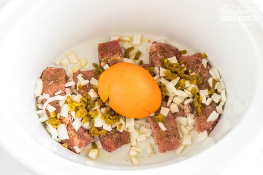 Country style boneless ribs in the crock pot with onions, jalapenos, and half an orange