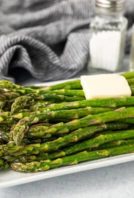 Side view of Sweet Sautéed Asparagus with butter and salt and pepper in the background.