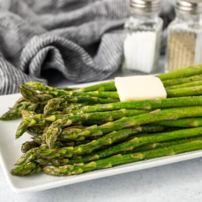 Side view of Sweet Sautéed Asparagus with butter and salt and pepper in the background.
