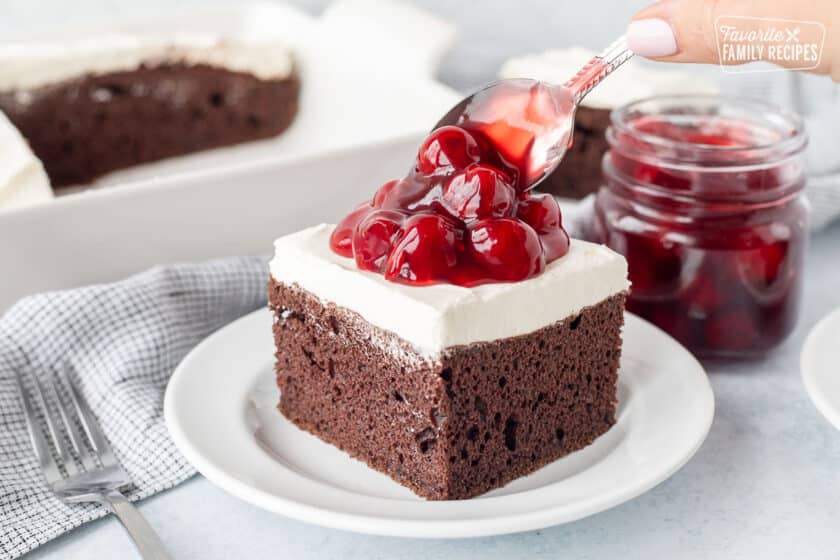 Topping Cherries on a slice of Chocolate Cake with cream cheese and cool whip frosting.