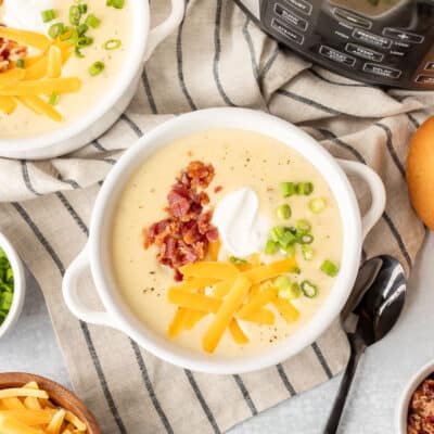 Two bowls of Instant Pot Loaded Potato Soup with bacon, sour cream, green onions and cheddar cheese.