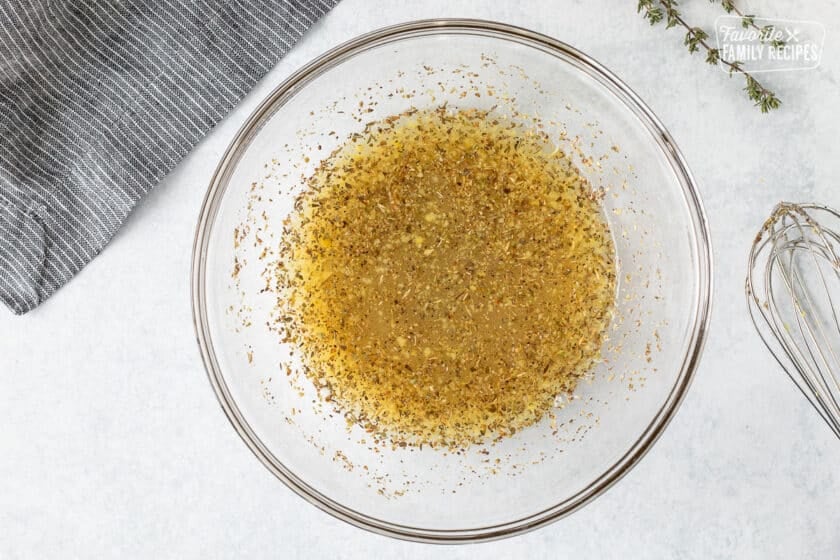 Bowl with marinade dressing and whisk on the side.