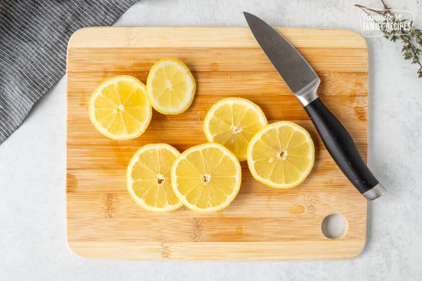 Cutting board with sliced lemons with a knife.