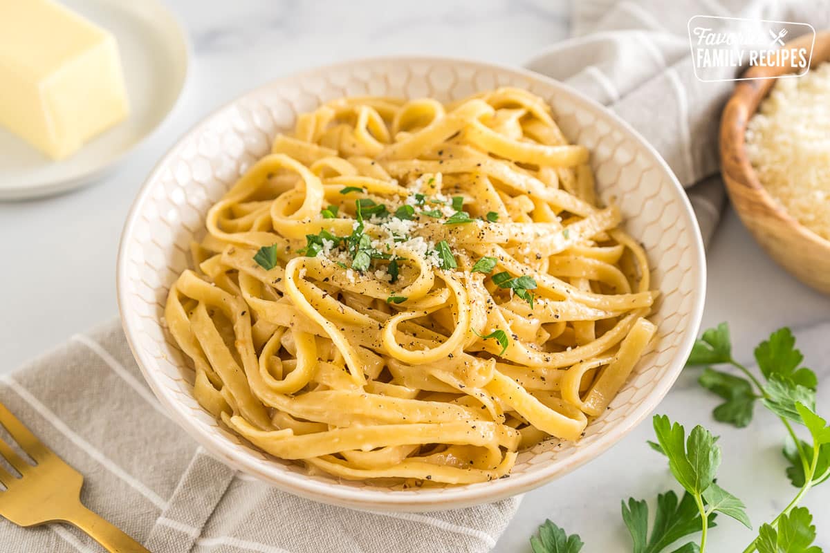 Buttered Noodles in a bowl topped with parsley, pepper, and parmesan