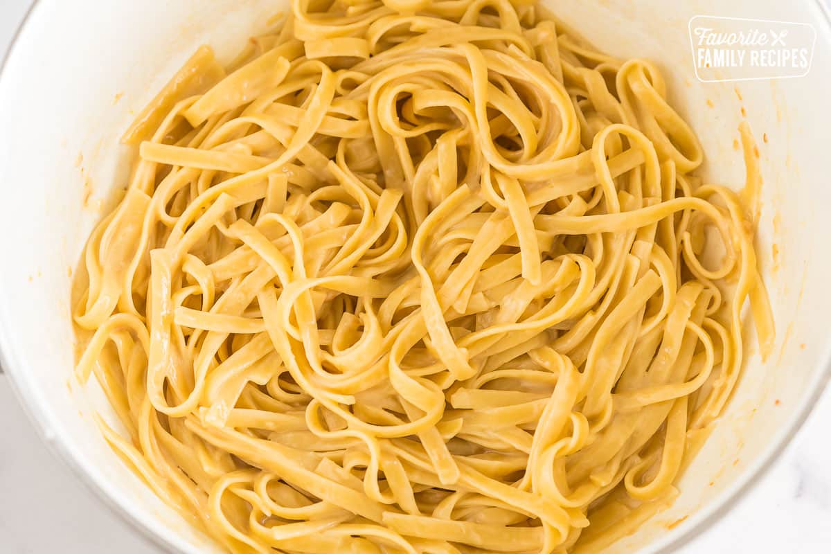 A pot full of fettuccine pasta, butter, cheese, and pasta water