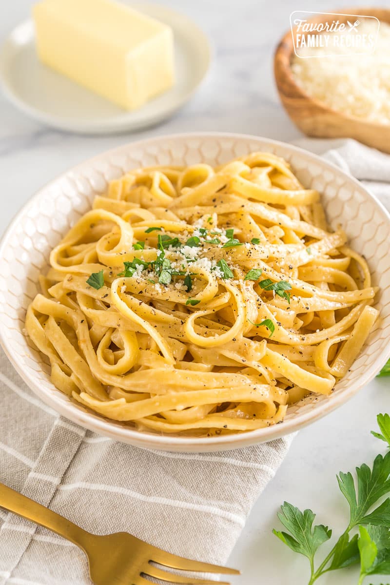 Buttered Noodles in a bowl topped with parsley, pepper, and parmesan