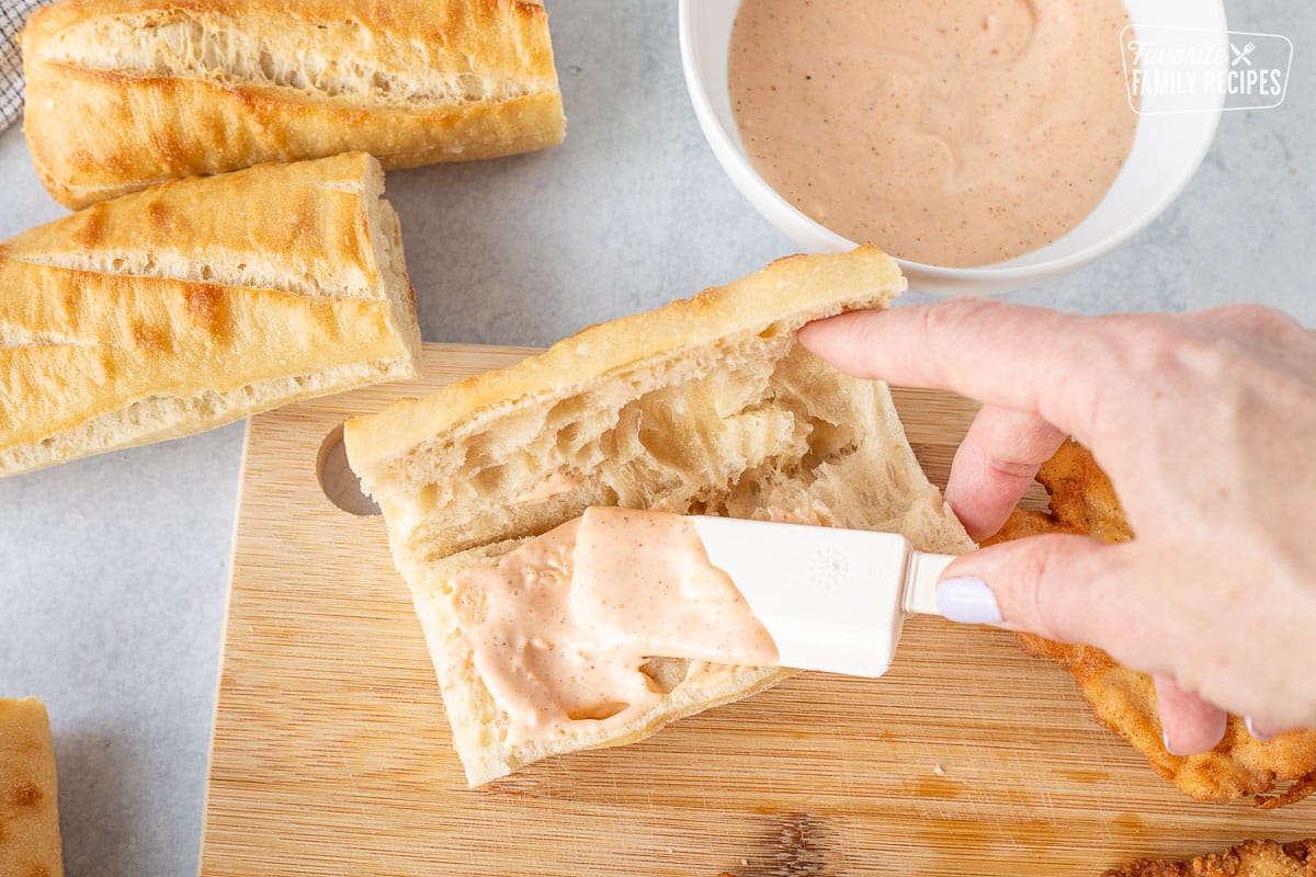 Spreading dressing on the roll with spatula.