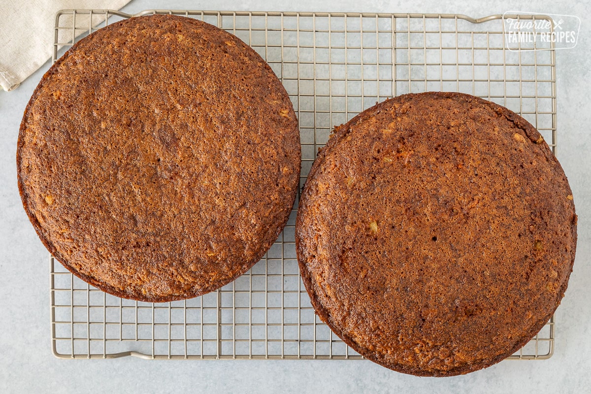 Two baked round carrot cakes on a cooling rack.