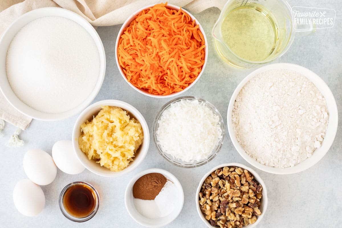 Ingredients to make Classic Carrot Cake including flour, sugar, oil, carrot, pineapple, coconut, walnuts, cinnamon, baking soda, salt, vanilla and eggs.