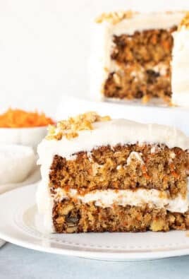 Slice of Classic Carrot Cake on a plate. Cake in the background on a stand.