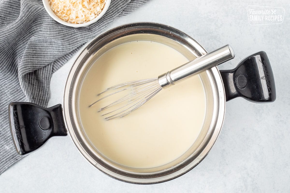 Sauce pan with creamy liquid and whisk.