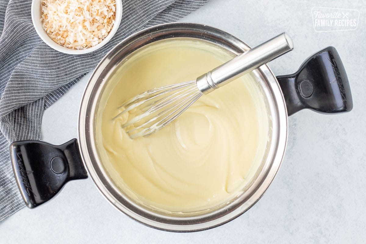 Sauce pan with thickened pudding mixture and a whisk.